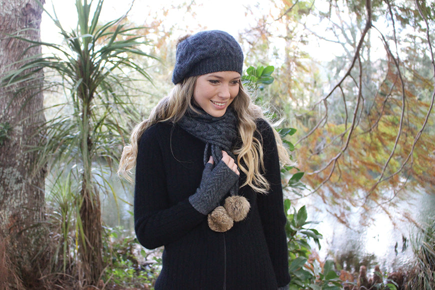 A relaxed cable knit beanie with rabbit fur pom pom. Colour - charcoal with natural pom pom.