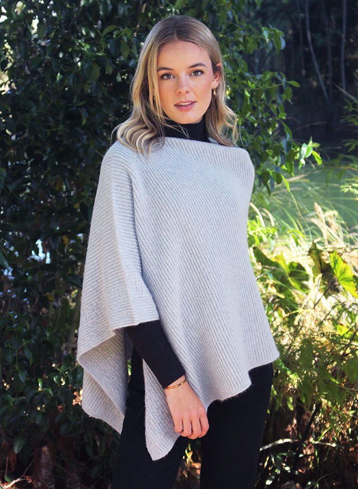 This asymmetrical poncho is a rib knit which also has a textured detail on one side. Soft, warm and available in five colours. Made in NZ by Lothlorian. Dove.