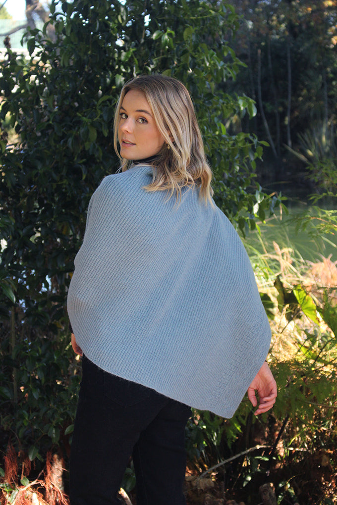 This asymmetrical poncho is a rib knit which also has a textured detail on one side. Soft, warm and available in five colours. Made in NZ by Lothlorian. Mist.