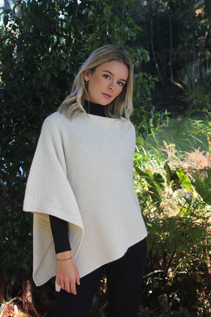 This asymmetrical poncho is a rib knit which also has a textured detail on one side. Soft, warm and available in five colours. Made in NZ by Lothlorian. Natural. 