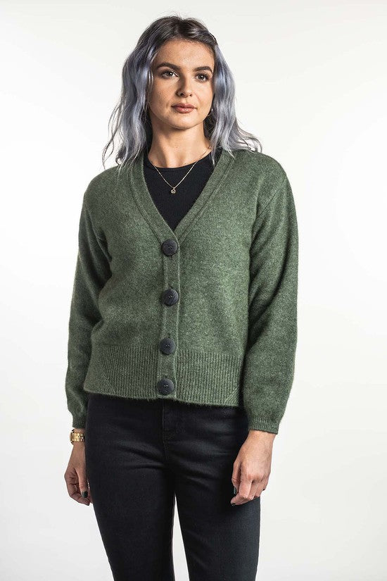 A modern twist on a V neck cardigan. This style is hip length and features oversize two tone buttons and a wide rib detail on the hem. In the beautiful new Koru shade of Moss. Includes a spare button. Made in NZ by Koru.  Moss.