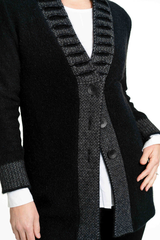 This stunning possum merino button jacket has a unique feature collar with strong vertical lines. A longline jacket that is extremely warm and cosy but is still very flattering to wear. Available in Black/Grey in sizes XS - XXL. Made by Koru in Warkworth, NZ. Black/Grey.