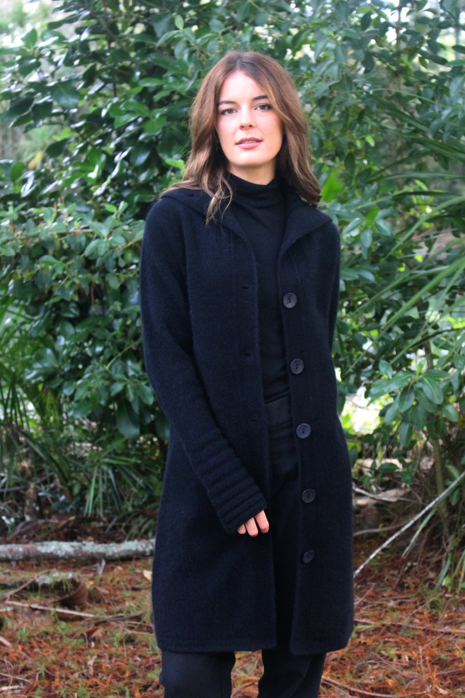 A heavier weight long coat in a possum merino blend. Has V-shaped rib detail at the collar and roll back cuffs with button through fastening. In black only and sizes S, M, L, XL, XXL. Made in NZ by Lothlorian for their Zinity Collection. 